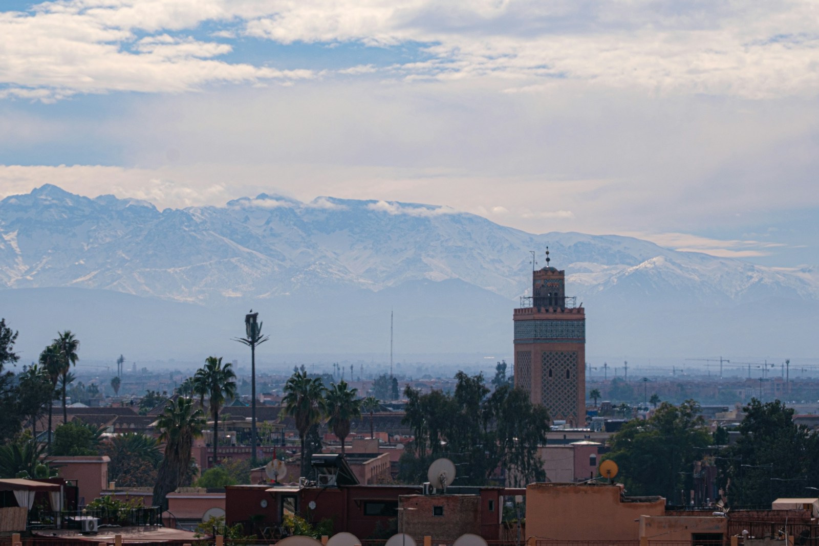 The Koutoubia minaret and palm trees in Marrakech, with the Atlas Mountains in the distance